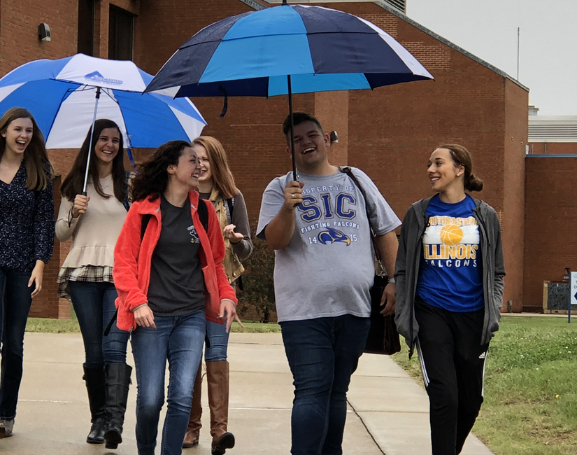 SIC Students walking across campus with umbrellas